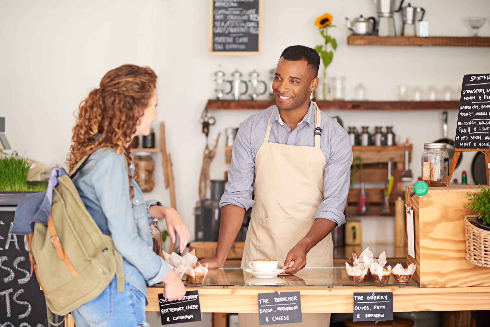 Man selling coffee to a woman at a coffee shop.